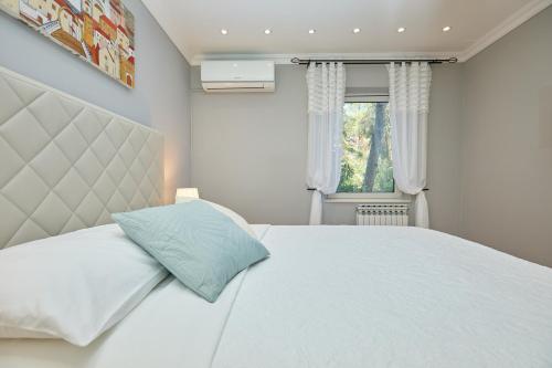 1 dormitorio con cama blanca y almohada azul en Hedera Estate, Hedera A3, en Dubrovnik