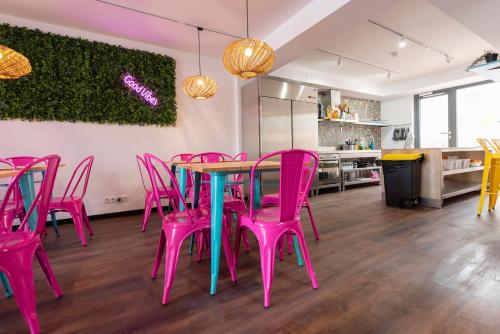 Zimmer mit einem Tisch und rosa Stühlen in der Unterkunft Hostelle - Women only hostel Barcelona in Barcelona