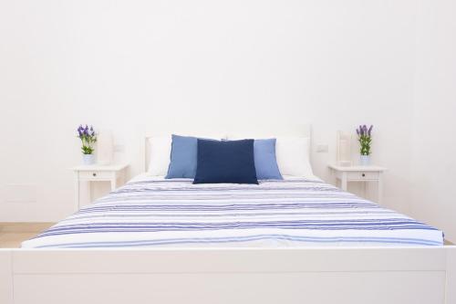 a bed with blue and white sheets and two white tables at Ciatu Miu in Noto