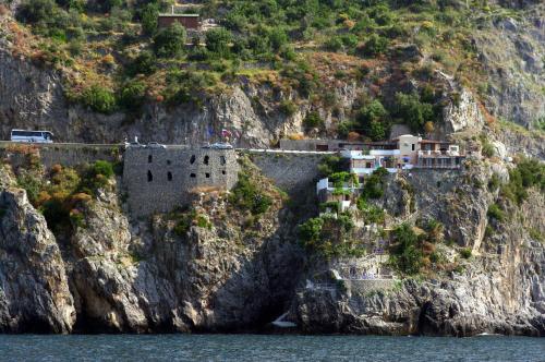 a castle on a cliff next to the water at La Locanda Del Fiordo in Furore