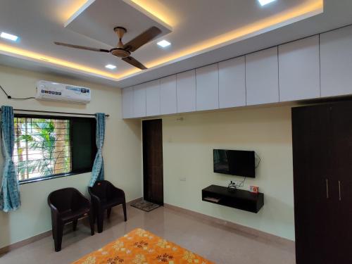 a living room with a tv and a couch and chairs at Rama Niwas Beach Home Stay in Pawas