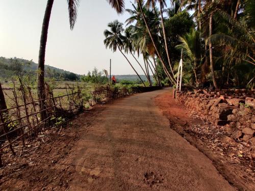 a dirt road with palm trees and a fence at Rama Niwas Beach Home Stay in Pawas
