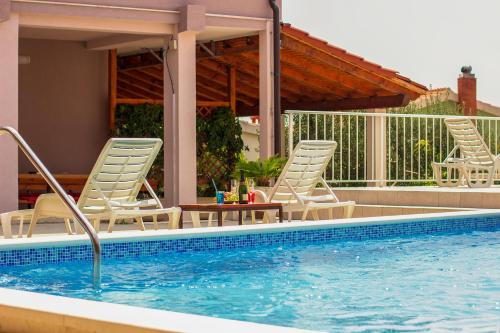 a swimming pool with chairs and a table next to a swimming pool at Villa Ljetni San in Omiš