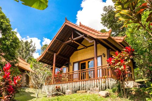 une maison avec un balcon dans un jardin dans l'établissement Bali Palms, Tabanan, à Tabanan