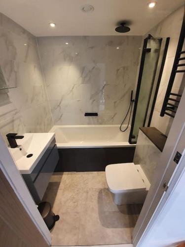 a bathroom with a sink and a toilet and a tub at Sycamore Lodge Kent With EV Zappi type 2, swimming pool for a fee in Sellindge