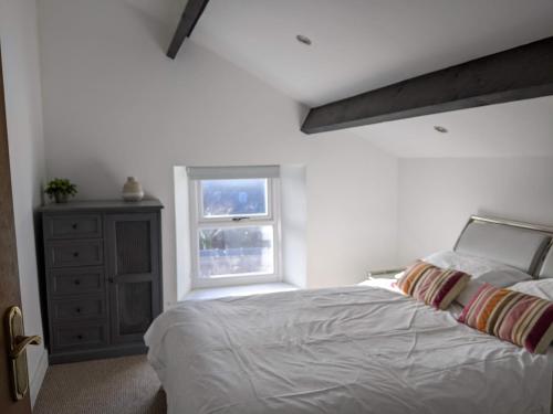 a bedroom with a white bed and a window at Millmoor Cottage - Broad Haven in Broad Haven