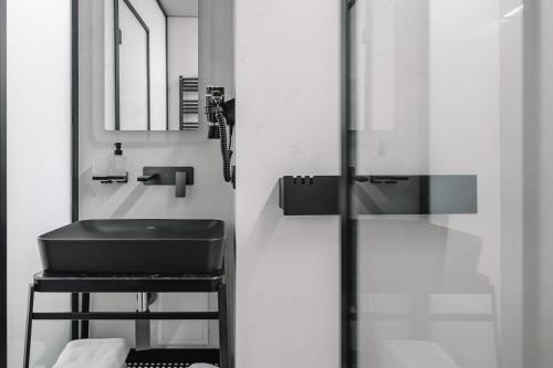 baño con lavabo, espejo y taburete en Ribas Rooms Lutsk, en Lutsk
