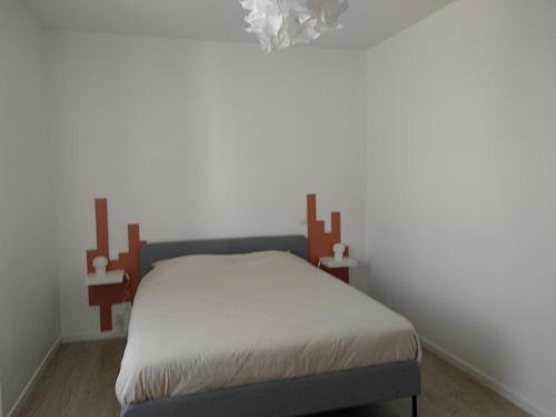 Cama en habitación con pared blanca en La Petite Maison en Rezé
