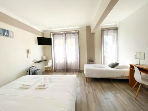 a room with two beds and a desk and two windows at La Marine in Carnac