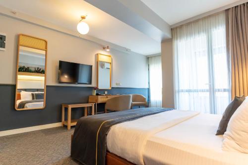 a hotel room with a bed and a desk and a television at Viva La Vita Hotel in Konak