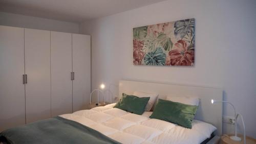 um quarto com uma cama branca e almofadas verdes em Sunnyside Apartment in the City Center em Ljubljana