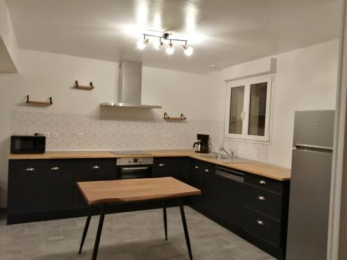 cocina con armarios negros y nevera de acero inoxidable en Le Tiluce en Aunay-sur-Odon