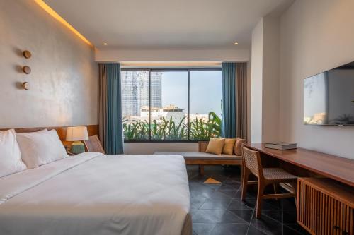 a hotel room with a large bed and a desk at Le Mint Hotel Quy Nhơn in Quy Nhon