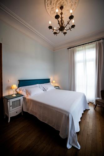 a bedroom with a large white bed and a chandelier at POSADA SEMILLA in La Abadilla