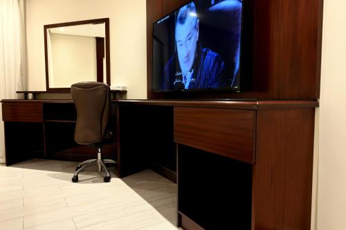 a hotel room with a television and a chair at Quiet Dreams - Serviced Apartments King abdul Aziz Street Branch in Jeddah