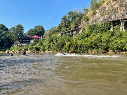 a group of people riding in boats on a river at The Villa Sai yok noi in Khlong Luang