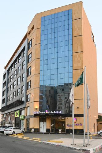 a large building with a glass facade on a street at Quiet Dreams - Serviced Apartments King abdul Aziz Street Branch in Jeddah