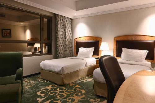 a hotel room with two beds and a chair at Quiet Dreams - Serviced Apartments King abdul Aziz Street Branch in Jeddah