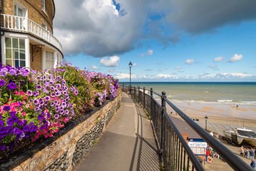 a building with flowers on a wall next to the beach at Beach House in Cromer