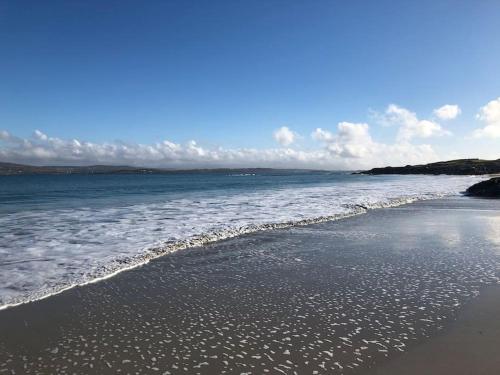 a beach with waves coming in from the ocean at Townhouse Clifden: Located in the heart of Connemara in Clifden