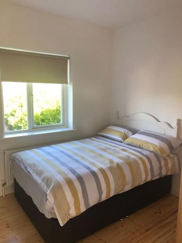 a bedroom with a bed with a striped comforter and two windows at Townhouse Clifden: Located in the heart of Connemara in Clifden