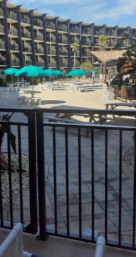 a beach with tables and umbrellas in front of a building at Daytona Beach Hawaiian Inn in Daytona Beach