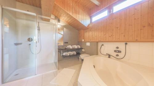 uma casa de banho com uma banheira, um chuveiro e um WC. em Chalet Lindau Fieberbrunn - by ONE VILLAS em Fieberbrunn