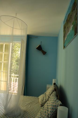 een slaapkamer met een bed en een blauwe muur bij HORIZON 180° in Le Bois de Nèfles