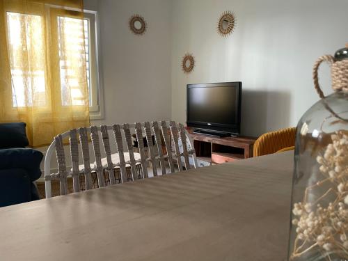 a living room with a table and a television at Chez Malouga in Ham