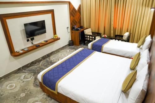a hotel room with two beds and a flat screen tv at Hotel Udupi Inn, Udupi in Udupi
