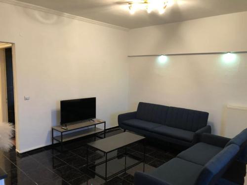 a living room with two blue couches and a tv at Luxury Apartments Christos in Gouvia
