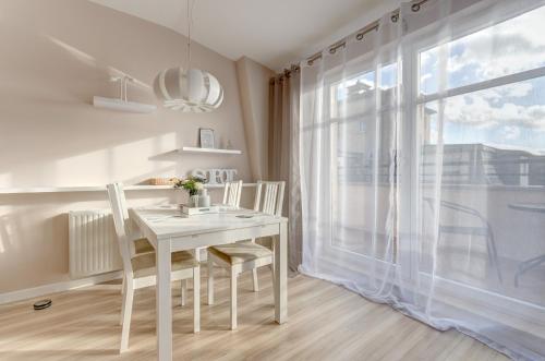 een witte eetkamer met een witte tafel en stoelen bij Dom & House - Apartments Parkur Sopot in Sopot