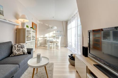 a living room with a couch and a tv at Dom & House - Apartments Parkur Sopot in Sopot