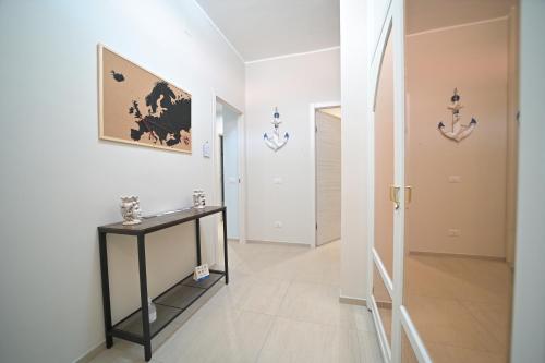 um corredor branco com uma mesa e um quadro na parede em Villa Borgo dei Pescatori em Torre Faro