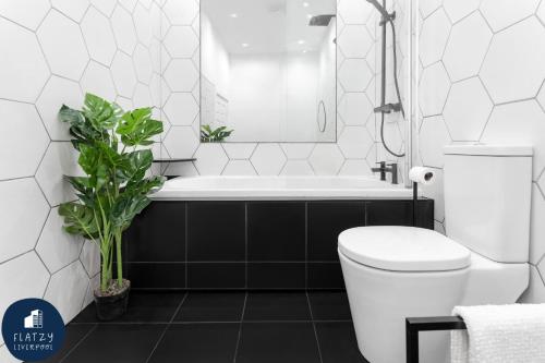 a bathroom with a tub and a toilet and a plant at FLATZY - Victoria Street Apartment - Heart of City Centre in Liverpool