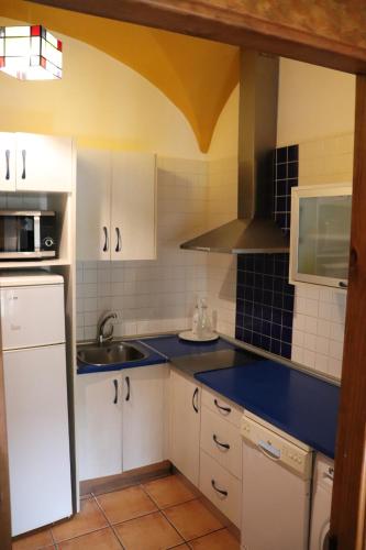 una cocina con armarios blancos y encimeras azules en Apartamentos Las Buganvillas, en Cáceres