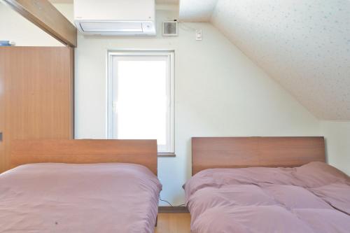 two beds in a bedroom with a window at LAKE TOYA Great view log cabin in Lake Toya