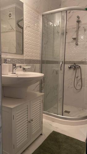 a white bathroom with a sink and a shower at Beach Residence Pomorie in Pomorie