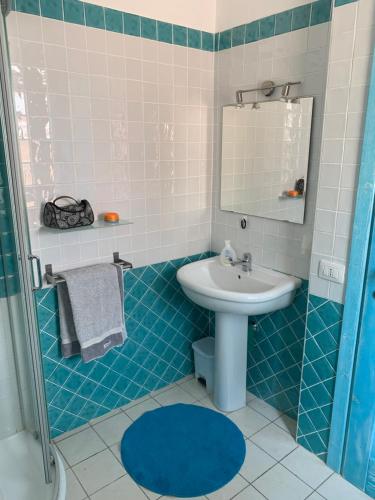 La salle de bains bleue et blanche est pourvue d'un lavabo et d'un miroir. dans l'établissement Grazioso e confortevole appartamento a Chia, à Chia