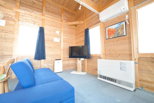 a living room with a blue couch and a tv at LAKE TOYA Logde SIGRA in Lake Toya