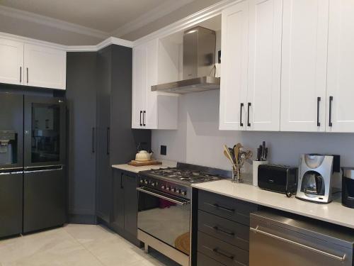 La cuisine est équipée de placards blancs et d'un four avec plaques de cuisson. dans l'établissement Best of Both in Pecanwood Estate, à Hartbeespoort