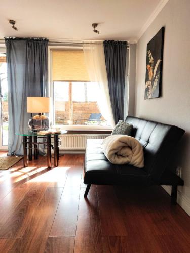 a living room with a black couch and a table at SB Apartment with Sauna in Kołobrzeg