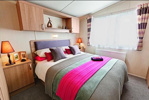 a bedroom with a large bed with red pillows at COASTAL CARAVAN ELIE sleeps 6 in Elie