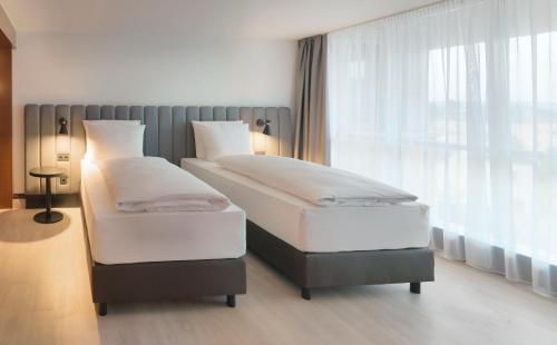 two twin beds in a room with a window at Radisson Blu Park Hotel & Conference Centre in Dresden