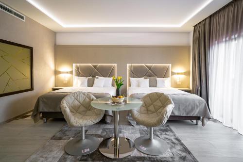 a hotel room with two beds and a table and chairs at Hotel Eden Garden Spa in Câmpulung Moldovenesc