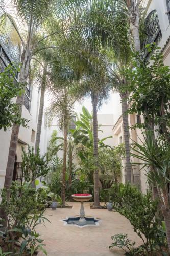 a courtyard with palm trees and a table in front of a building at Riad Fes - Relais & Châteaux in Fès
