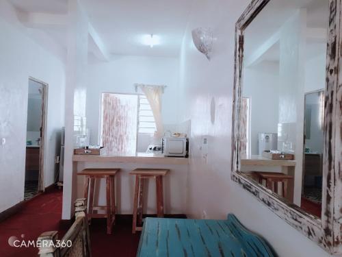 una habitación con 2 espejos y una barra con taburetes en Diwani Cottage en Malindi