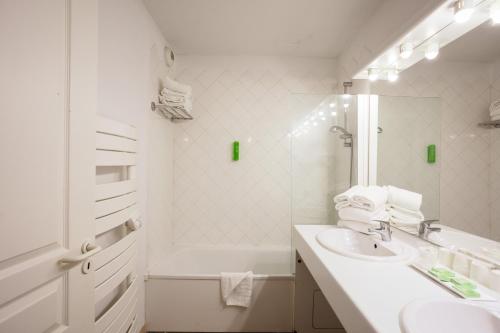 a white bathroom with a sink and a tub at Résidence Les Jardins de Massane in Baillargues