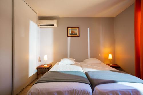 twee bedden in een kleine kamer met twee lampen bij Résidence Les Jardins de Massane in Baillargues