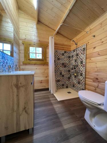 ein Holzbadezimmer mit einem WC und einer Dusche in der Unterkunft Cabaña Garrote Gordo in Segura de la Sierra